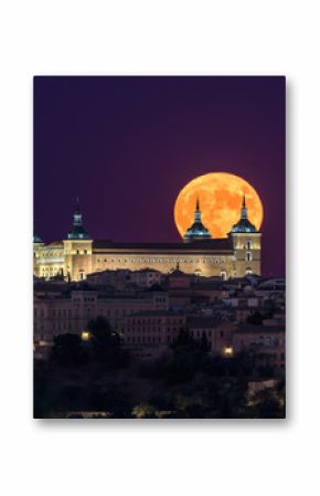 Wonderful scenery of illuminated ancient palace built over town in colorful night with full red Moon in Toledo