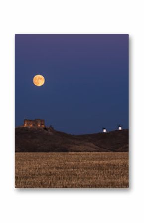 From below picturesque scenery of abandoned aged fortress on top of mountain illuminated by full Moon at night in Toledo