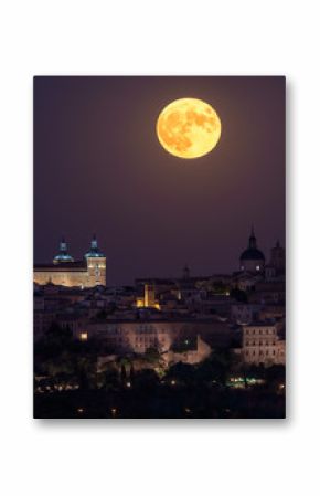 Wonderful scenery of illuminated ancient palace built over town in colorful night with full red Moon in Toledo