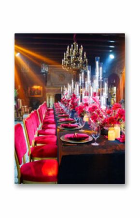 Beautiful festive table setting with fresh red flowers, napkins and candles.
