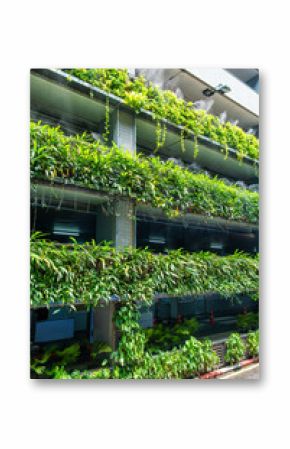 Vertical garden with green foliage and mist irrigation on multi-level facade of parking garage combining sustainable design with functional urban architecture in Bangkok city, Thailand