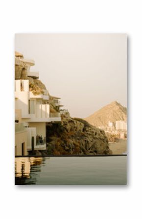 Sunlit cliffside villas overlooking Cabo San Lucas coastline and sea