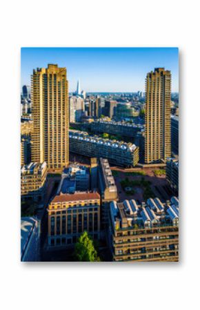 Colorful aerial view of London's Barbican Estate with high-rise buildings, modern architecture, and city skyline under a blue sky