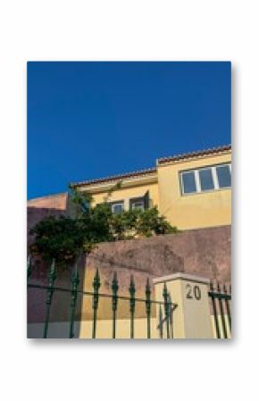 Sunlit ochre house with verdant vines celebrates La Tomatina vibrance, framing Fiesta de San Juan's azure sky