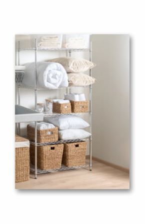 Interior of Bright Modern Laundry Room with White Duvet, Towels, Cozy Pillows, and Wicker Baskets on Adjustable Metal Storage Rack with Shelves, Chrome Wire Shelving Unit, Over Wooden Flooring.