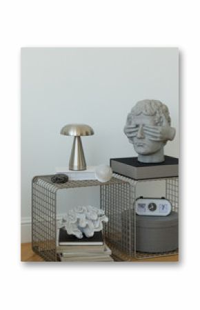 Detailed view of minimalist side table with modern sculpture, books and metallic lamp. Design and curated styling.