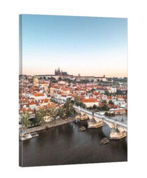 A breathtaking early morning view of Prague as the sun rises, illuminating the historic Charles Bridge and Hradcany Castle, with reflections dancing on the calm Vltava River.