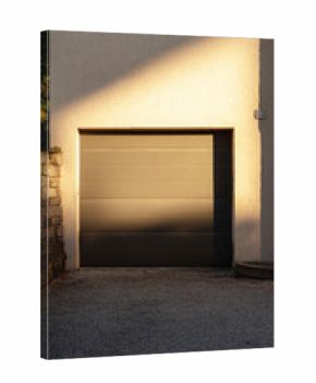 A garage door stands prominently against a textured wall, featuring sleek design elements and subtle shadows from the afternoon light, augmenting the home curb appeal