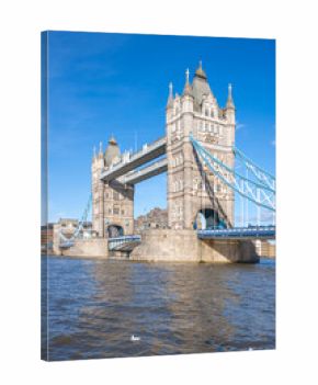 Tower Bridge stands majestically over the River Thames on a clear day, showcasing its iconic architecture and blue suspension cables. Boaters can be seen navigating the waters below.