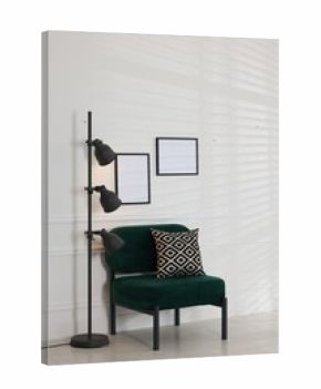 Stylish lamp, comfortable armchair with cushion and picture frames on white wall indoors