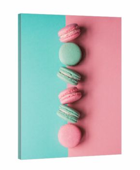 Line of pink and teal macaron cookies on colorful background.