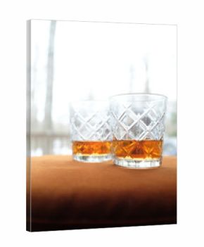 Two glasses of whiskey on orange velvet in cozy woods cabin