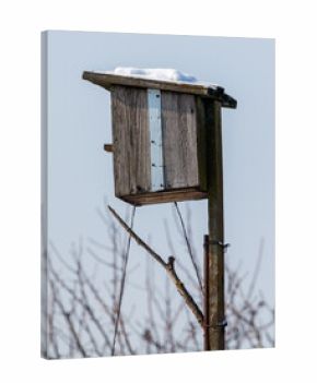 A wooden birdhouse is on a pole