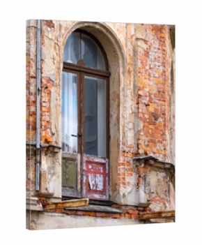 Weathered arched doorway with old wooden door, destroyed balkony, peeling paint and exposed brick