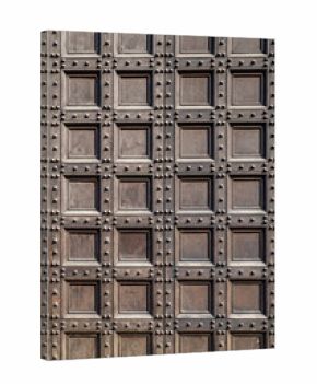 Old wooden door with square carved panels. Vintage texture of historic entrance. Antique architectural detail with geometric wood pattern. Medieval door design with decorative metal studs.