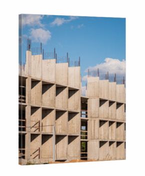 A construction site showcases a unique concrete building with exposed beams under a blue sky