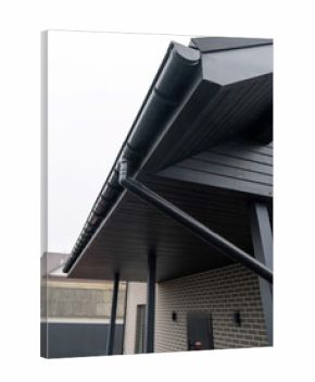 Black gutter system with downspout on modern brick house terrace roof