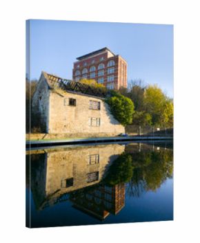 Derelict industrial building with perfect mirror reflection in calm canal at sunrise, England, UKcastle on the river