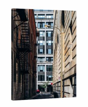 Montreal, Canada - August 14, 2025: narrow alleyway between historic and modern buildings with fire escapes and person walking