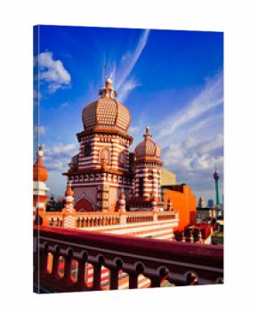 Spectacular view of the historic Minarets of the Jami Ul Alfar Mosque in contrast with the landmark 351m tall Lotus Tower with bright blue skies in Colombo,Sri Lanka
