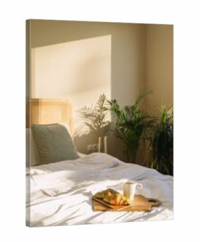 Light fills a cozy hotel bedroom with a bed and breakfast tray on the side