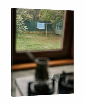 Backyard clothesline with towel seen through window from kitchen with kettle in foreground authenticity inclusivity