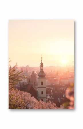 Baroque chapel bell tower steeple at historical part of city on the background of an orange red sunrise sky.