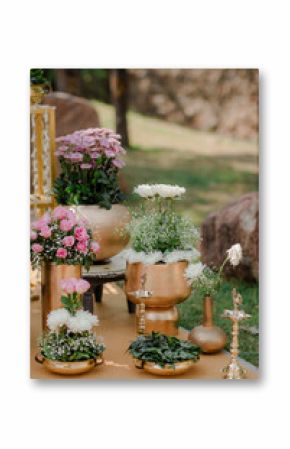 Elegant flower arrangements in gold pots and vases, featuring roses, chrysanthemums, and greenery, create a vibrant display for an outdoor event.