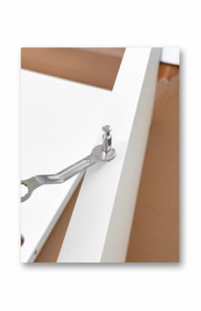 Assembling white furniture with metal wrench and cam lock fastener on brown surface