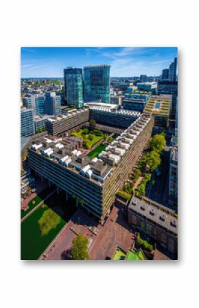 Colorful aerial view of London's Barbican Estate with high-rise buildings, modern architecture, and city skyline under a blue sky
