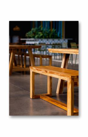Clean lines of modern wooden benches and tables in a contemporary cafe or eatery. Warm wood tones contrast with cool polished concrete floors, creating an inviting, minimalist interior space.