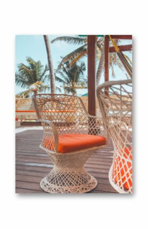 Woven patio chair with orange cushion on Belize deck by palms