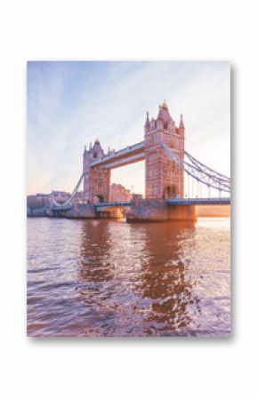 Tower Bridge stands majestically as the sun rises, casting warm hues over the Thames River. This iconic landmark is illuminated, showcasing its architectural beauty at dawn.