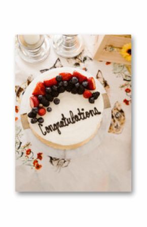 Celebration cake topped with berries and "Congratulations" text