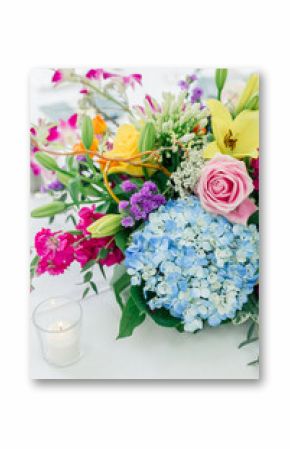 Colorful floral centerpiece with candle on white table