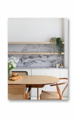 Bright modern dining room interior with wooden table and rattan chair positioned near kitchen area with marble backsplash creating an inviting space for peaceful moments at home