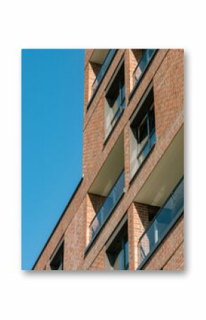 Contemporary brick apartment facade with glass balconies under clear blue sky in South Spain, ideal for real estate, architecture, and urban lifestyle visuals.