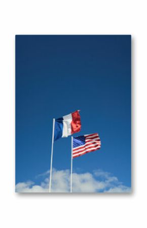 american and french flags in normandy france agains a blue sky