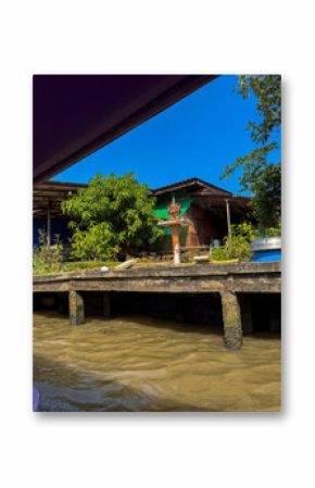 Traditional boat sailing on a river canal in Bangkok at sunset, picturesque water transport featuring a traditional sailboat gliding for transportation. Scenic cityscape with golden sunset.