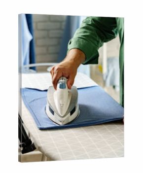 Ironing clothes at home with focus on a garment and an iron during a weekend morning