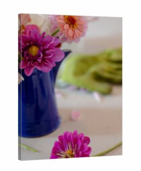Close-up of zinnia bouquet in enamel pitcher with gloves