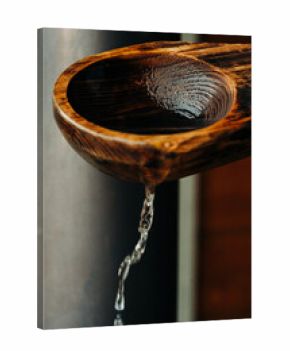 Close up of a wooden sauna spoon pouring water in a Swedish sauna