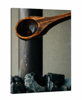 Wooden sauna spoon pouring water over hot sauna rocks in Sweden