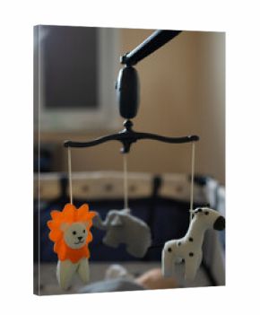 Soft toys shaped like a lion, elephant, and dog hang above a crib, creating a playful atmosphere in a bright nursery. A warm and inviting space for a baby to explore.