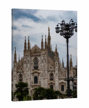Gothic cathedral facade in Milan. Beautiful architecture under cloudy sky. Travel landmark in Italy. Ornate stone details of Duomo. Historical church exterior view.
