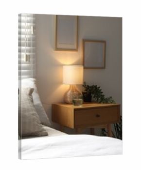 Lamp, glass of water and houseplant on wooden bedside table near large bed in bedroom. Interior design