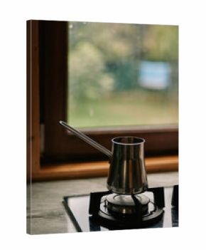 A gooseneck kettle rests on a gas burner in a home kitchen, metal shine and warm light create a cozy cooking scene.