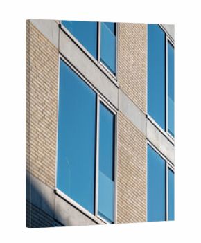 Modern building facade with large windows reflecting clear blue sky during daylight