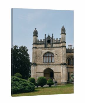 Historic building mansion castle architecture facade stone tower window arch with garden lawn and trimmed bushes