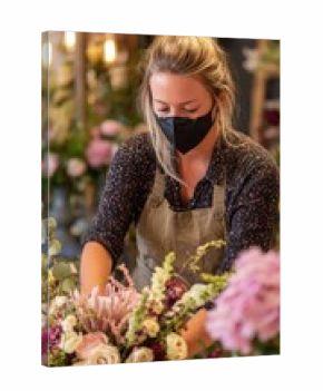 Side view of florist thoughtfully positioning various flowers and greenery to create a balanced and visually pleasing bouquet arrangement.